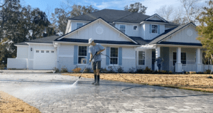 2 workers pressure washing an house and driveway